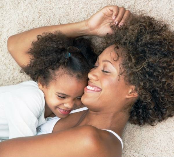 Mother and daughter laughing on clean light colored carpet